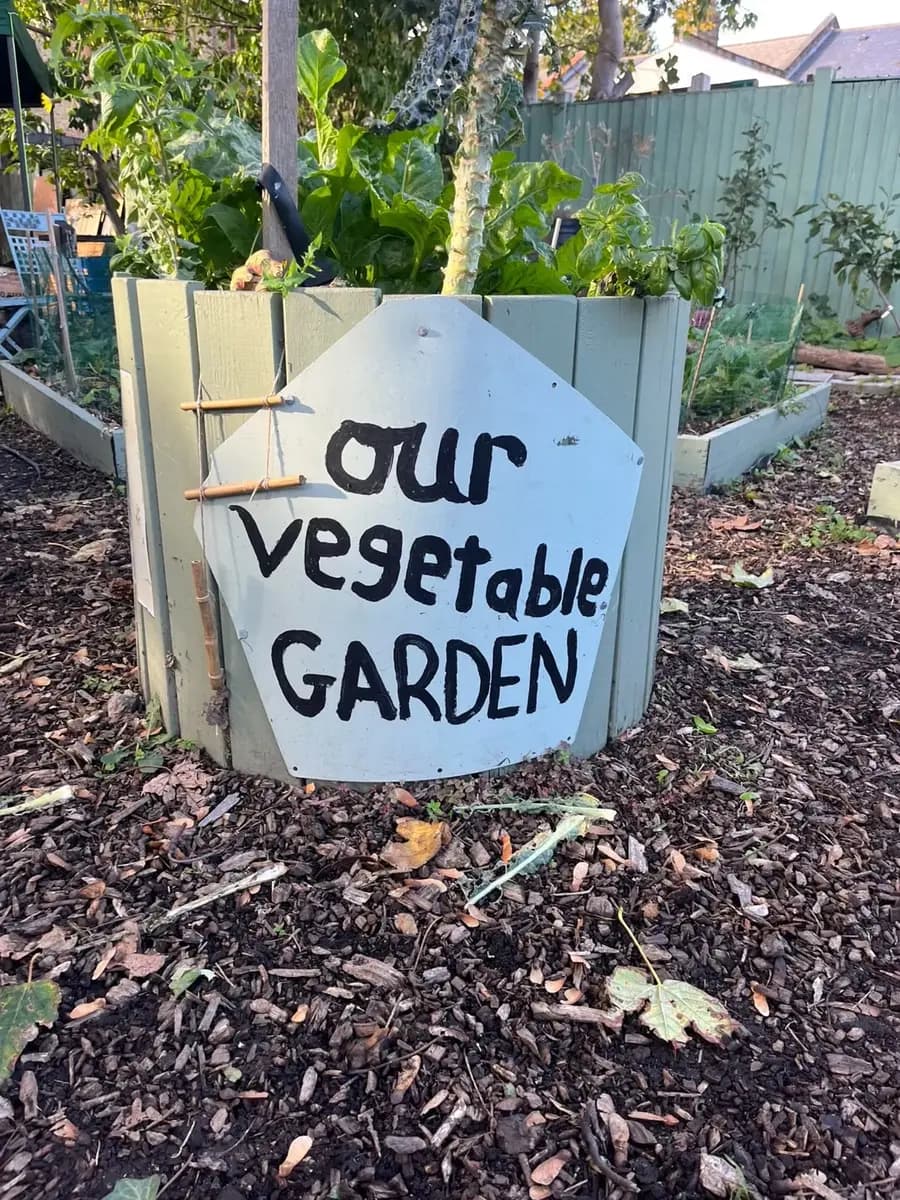 A painted board reading Our vegetable garden on a raised bed